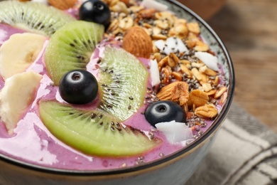 Delicious acai smoothie with granola and fruits on table, closeup