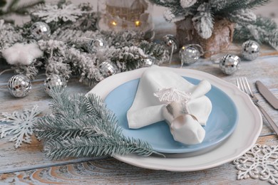 Festive place setting with beautiful dishware, cutlery and fabric napkin for Christmas dinner on light blue wooden table