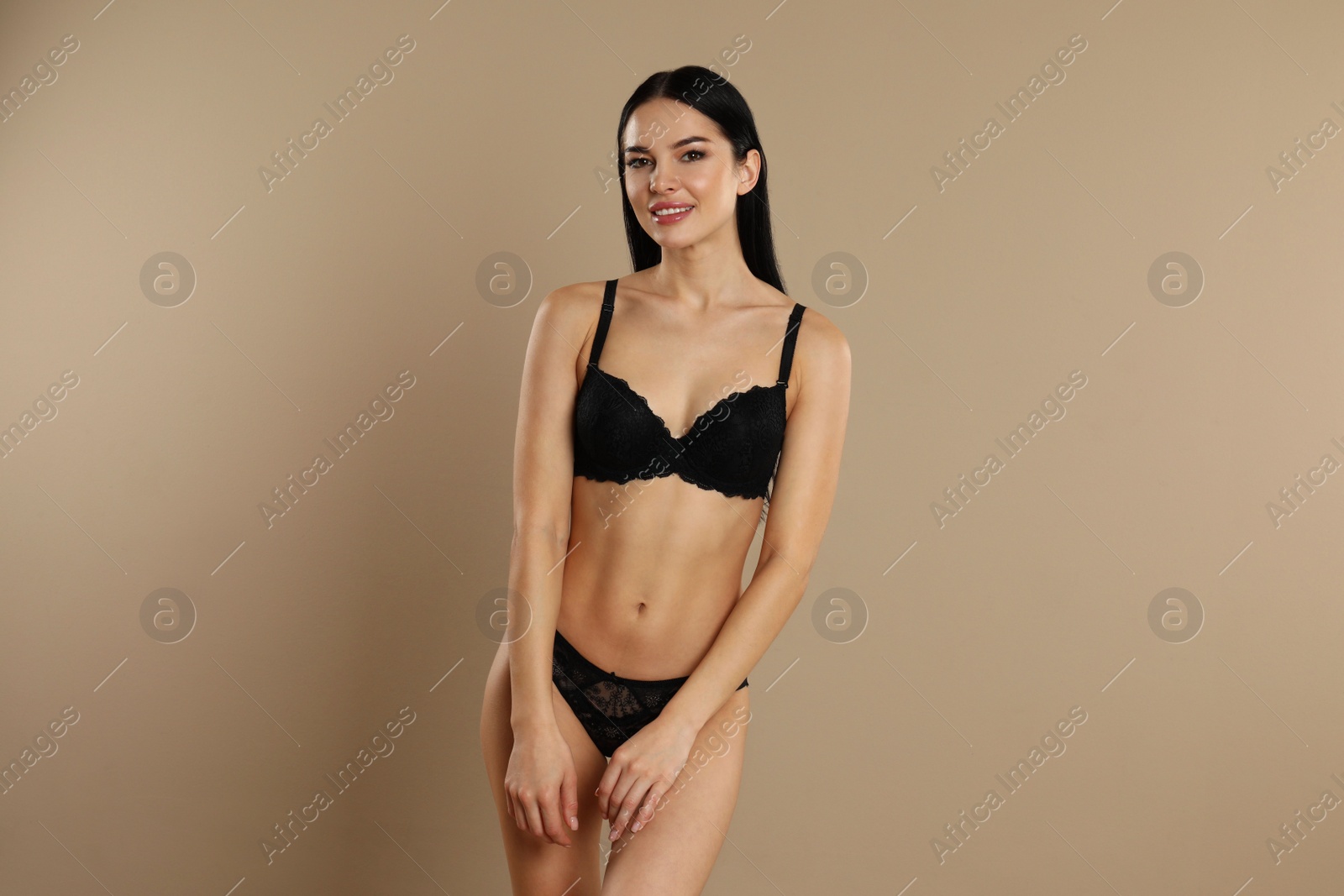 Photo of Beautiful young woman in black underwear on beige background