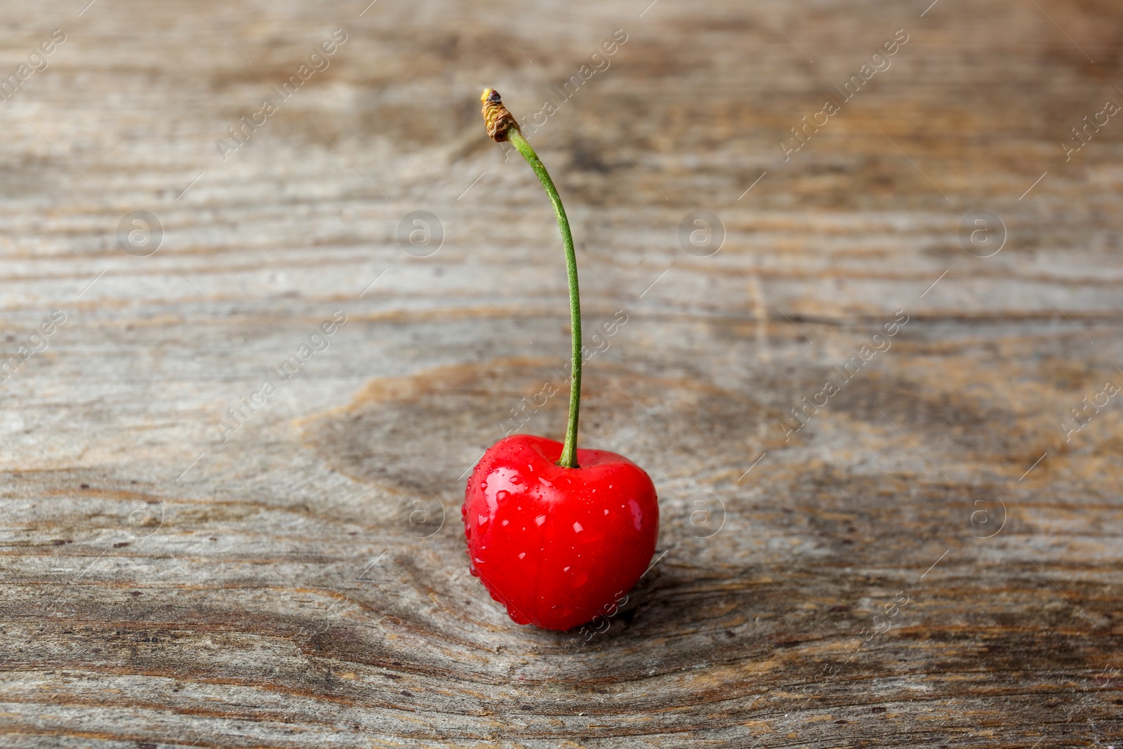 Photo of Ripe red cherry with water drops on wooden background