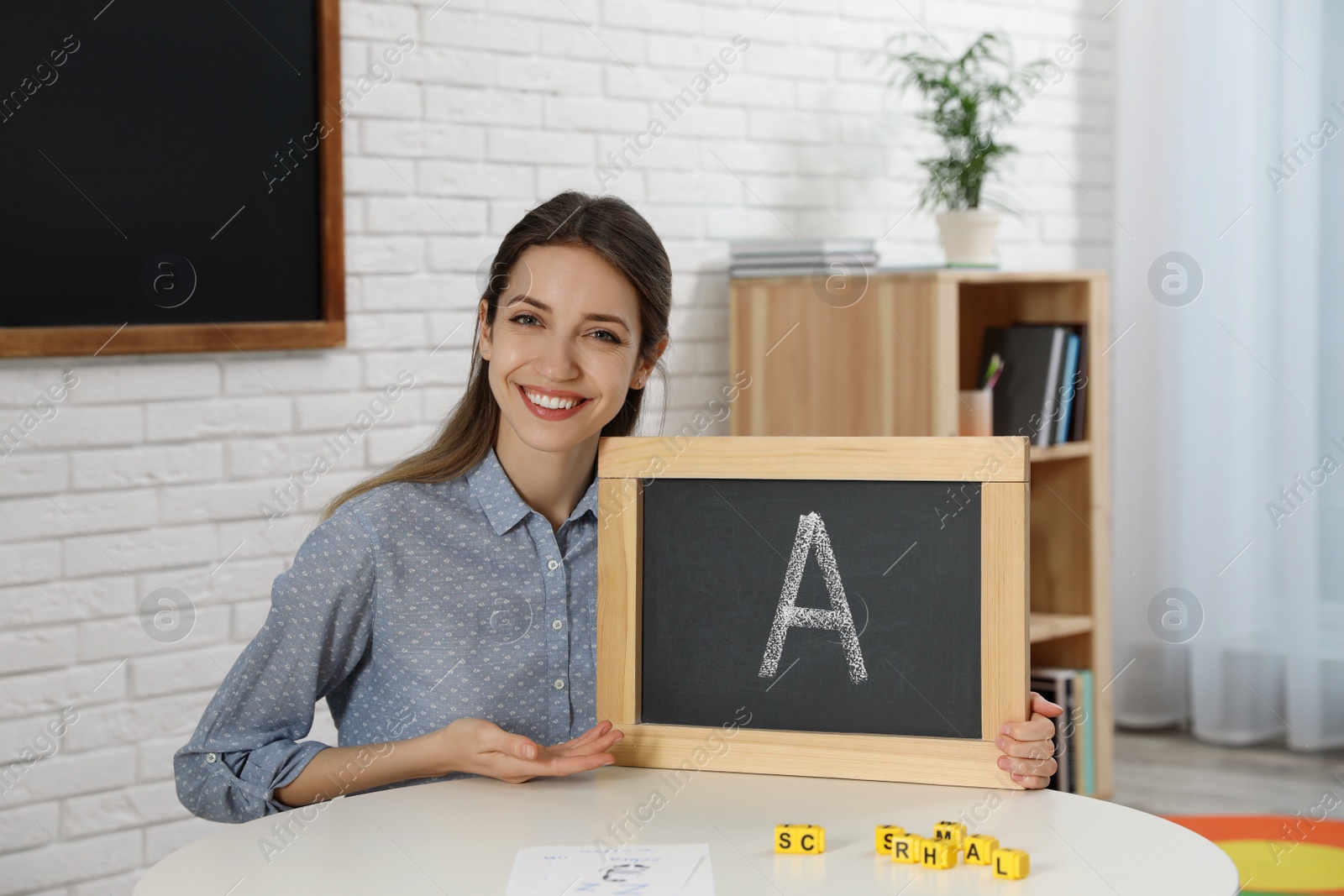 Photo of Happy female English teacher giving lesson in elementary school