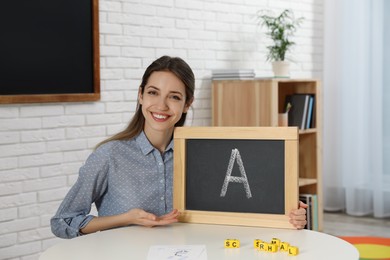 Happy female English teacher giving lesson in elementary school