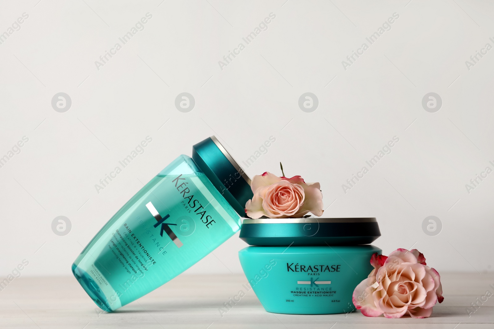 Photo of MYKOLAIV, UKRAINE - SEPTEMBER 07, 2021: Kerastase hair care cosmetic products and beautiful flowers on white wooden table