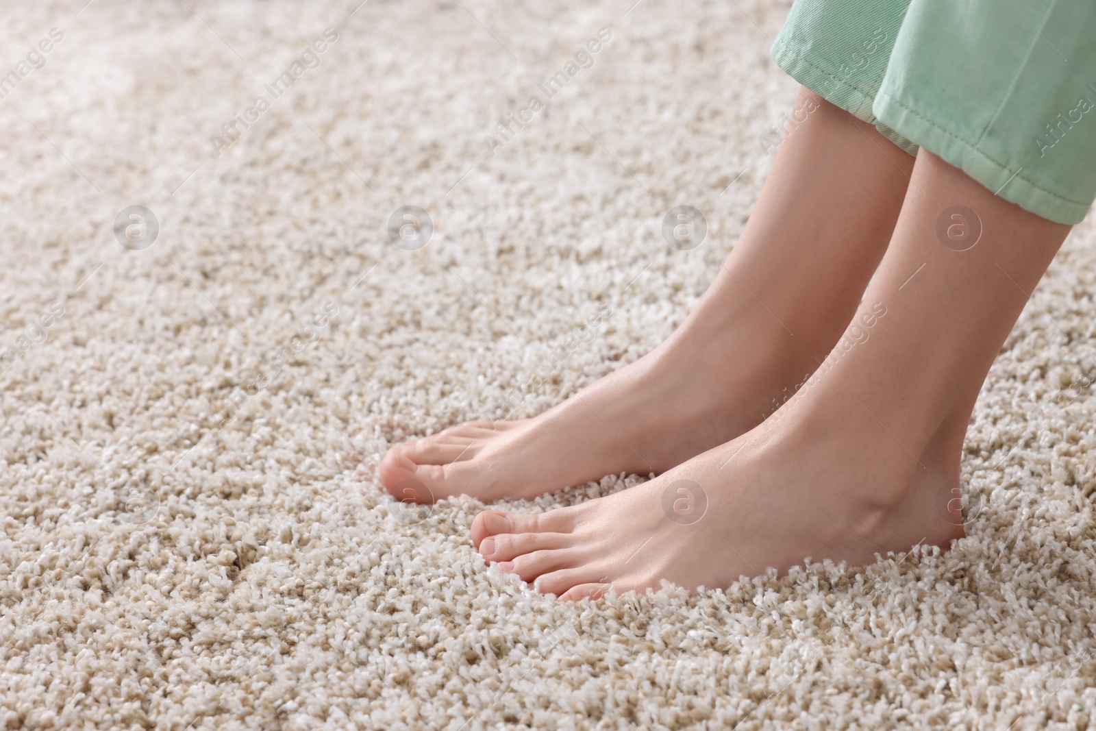 Photo of Woman on soft light brown carpet at home, closeup. Space for text