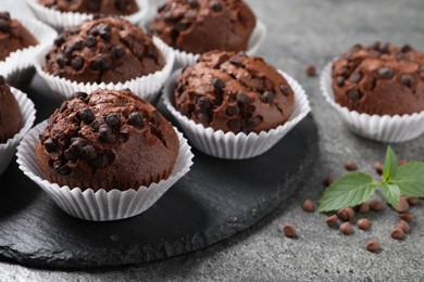 Photo of Tasty chocolate muffins on grey textured table, closeup