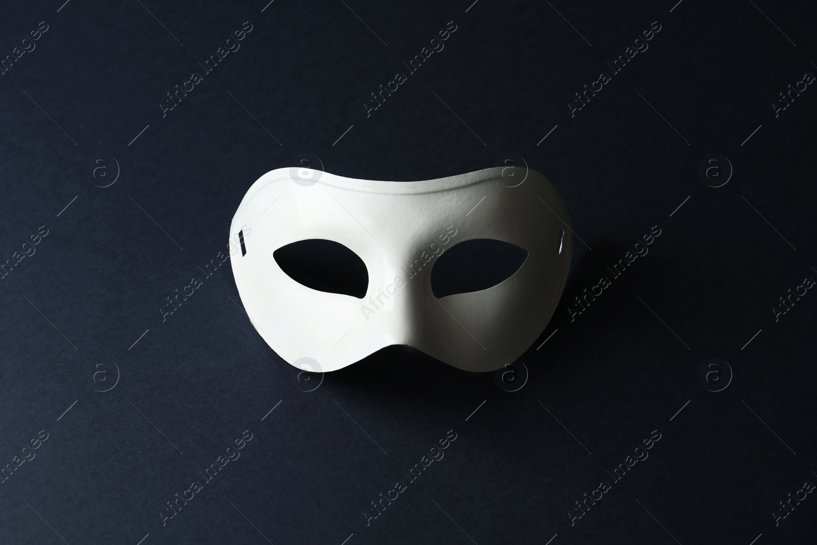 Photo of White theatre mask on black background, top view