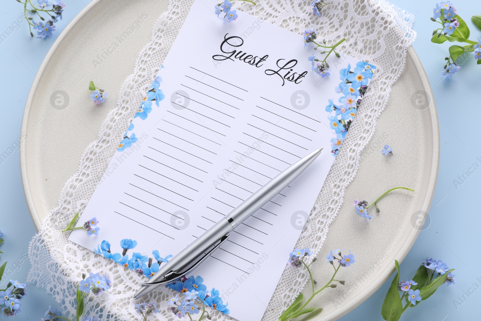 Photo of Plate with guest list, pen, lace and flowers on light blue background, flat lay. Space for text