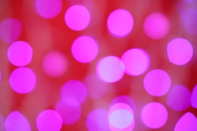 Blurred view of violet lights on red background. Bokeh effect