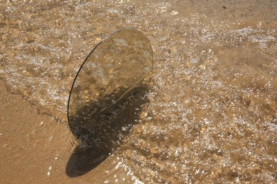 Photo of Round mirror reflecting sea on sandy beach. Space for text