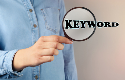 Image of Woman demonstrating word Keyword through magnifying glass, closeup