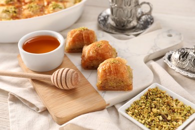 Photo of Delicious sweet baklava with pistachios and honey on table