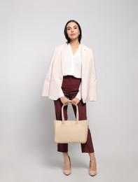 Young woman with stylish bag on white background