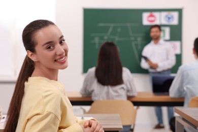 Happy woman at desk in class during lesson in driving school