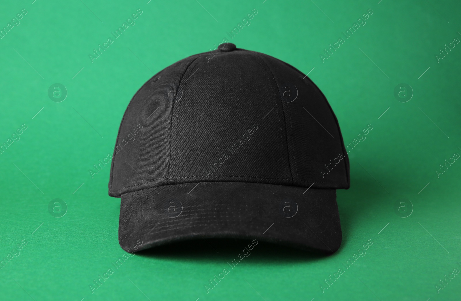 Photo of Stylish black baseball cap on green background