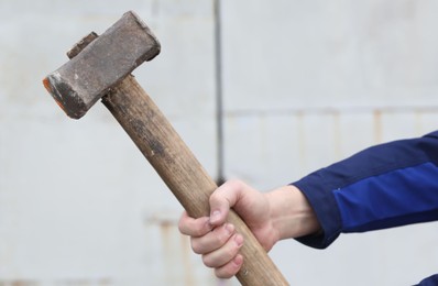 Man with sledgehammer on blurred background, closeup