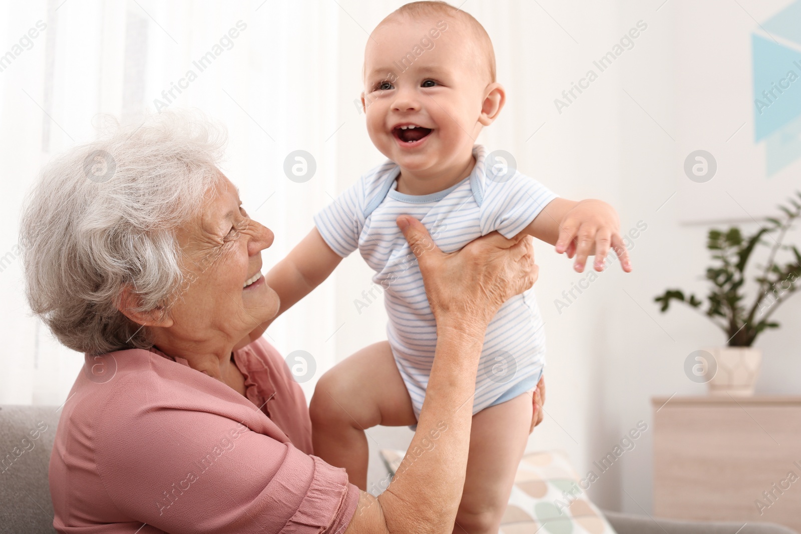 Photo of Happy grandmother with little baby at home