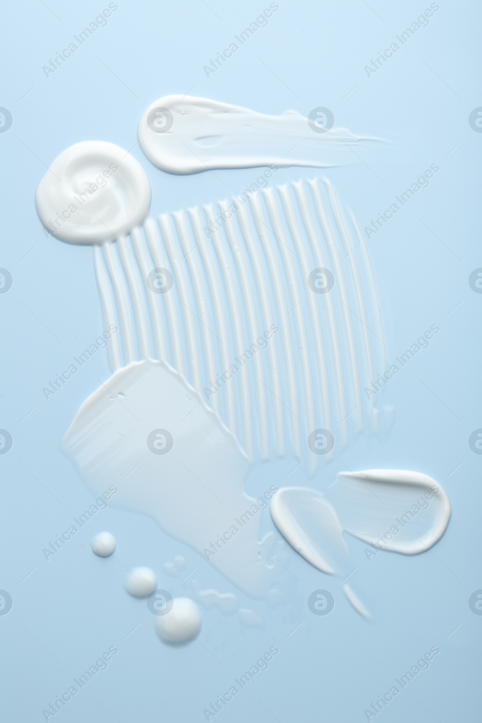 Photo of Samples of face cream on light blue background, top view