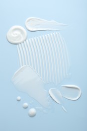 Photo of Samples of face cream on light blue background, top view