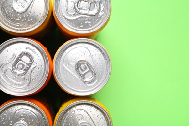 Energy drinks in wet cans on green background, top view. Space for text