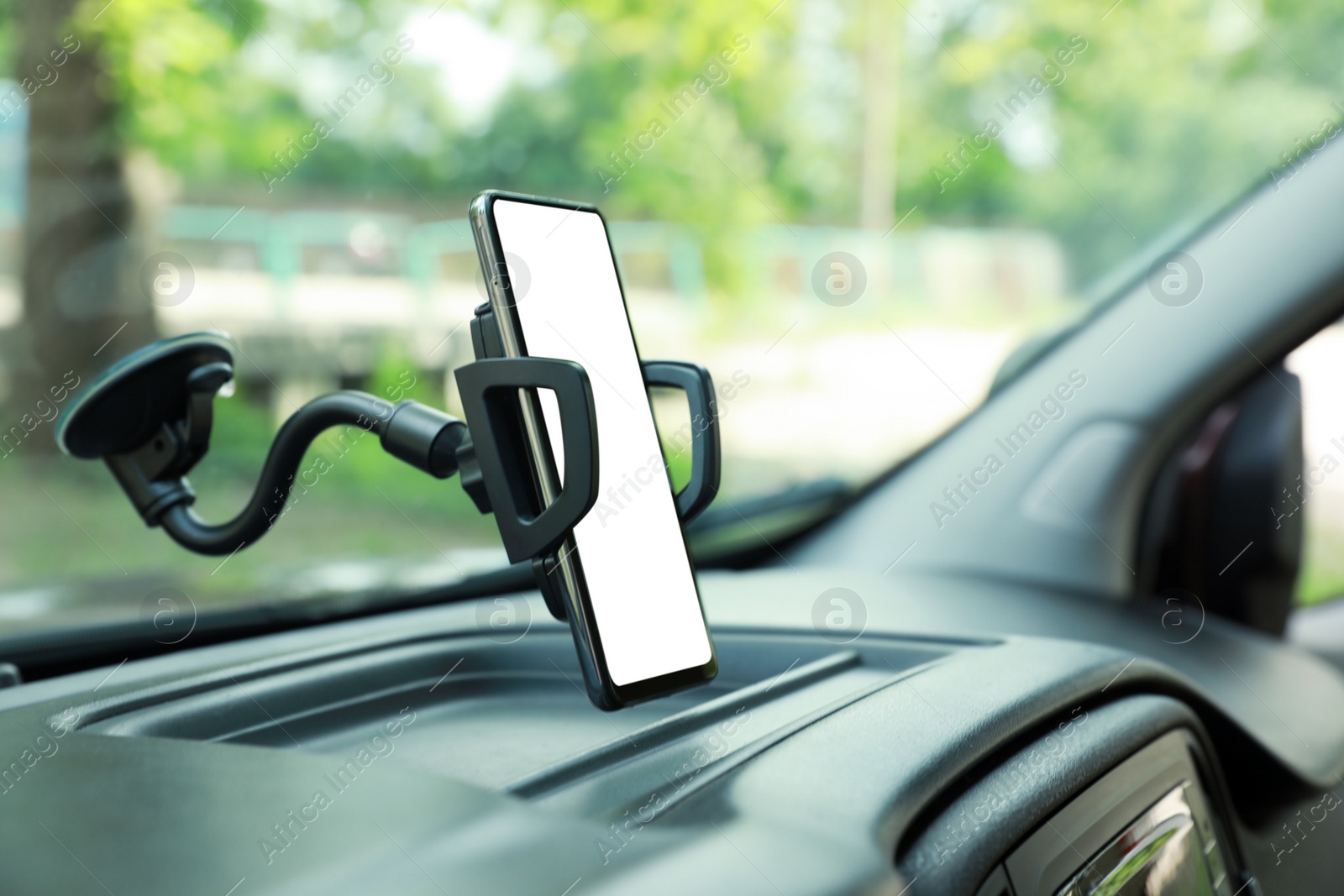 Photo of Car holder with modern mobile phone on windshield of automobile. Mockup for design