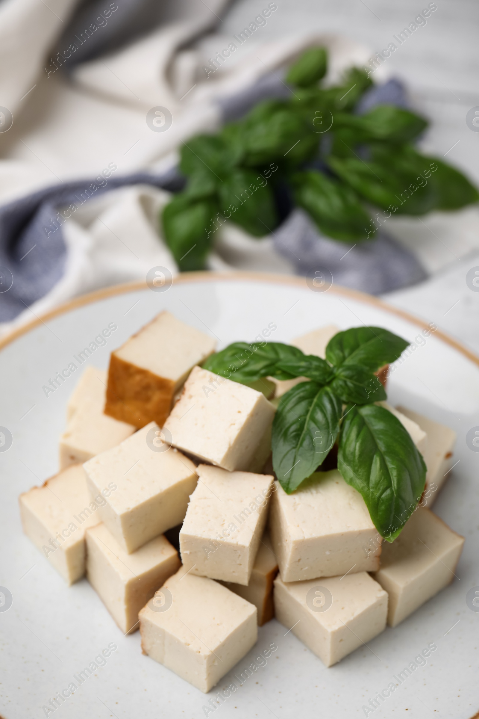 Photo of Plate with delicious smoked tofu and basil, closeup