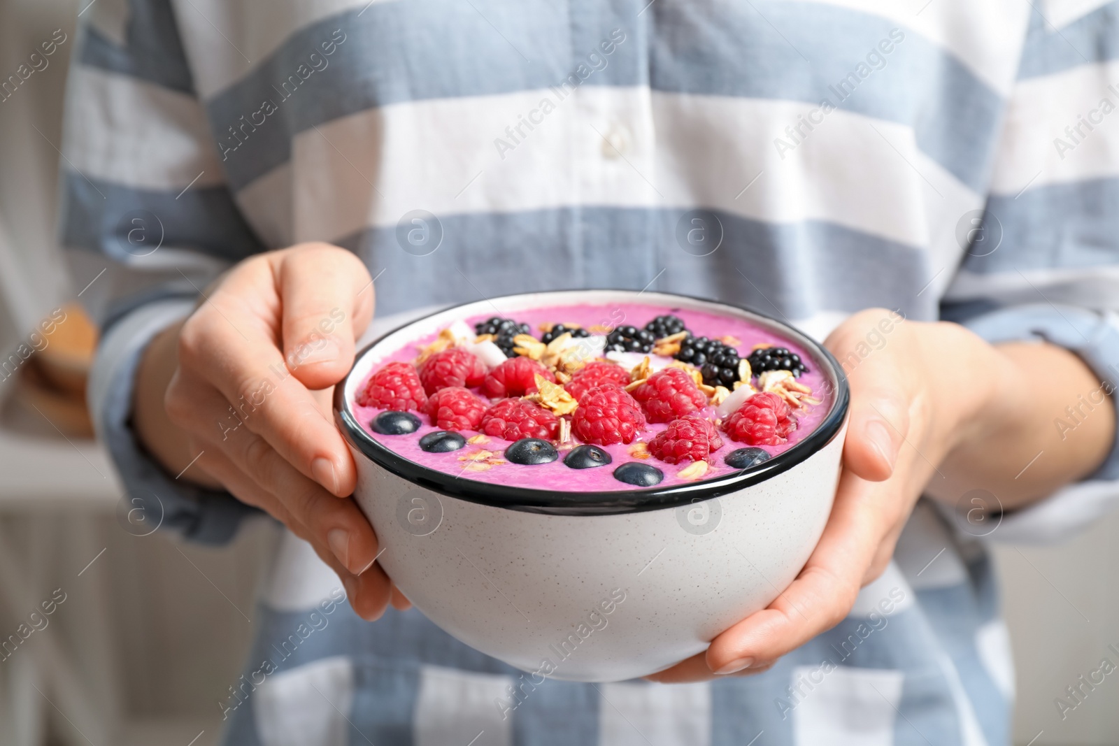 Photo of Woman holding bowl with tasty acai smoothie and berries, closeup