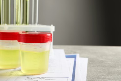 Photo of Containers with urine sample for analysis and test form on grey table in laboratory, space for text