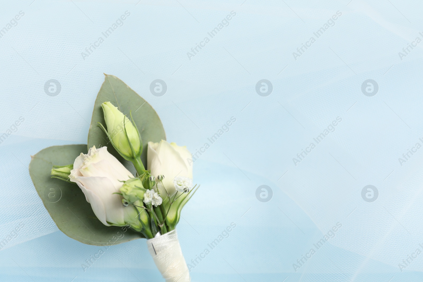 Photo of Wedding stuff. Stylish boutonniere and veil on light blue background, top view. Space for text