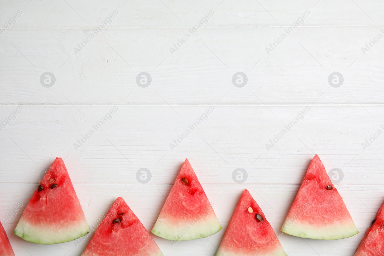 Photo of Watermelon slices on white wooden background, flat lay. Space for text