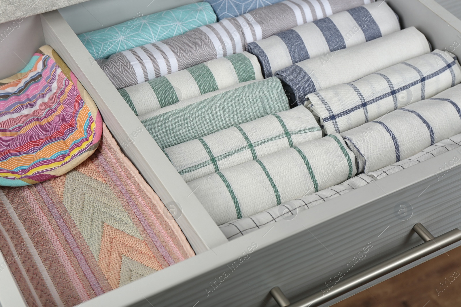 Photo of Open drawer with folded towels, closeup. Order in kitchen