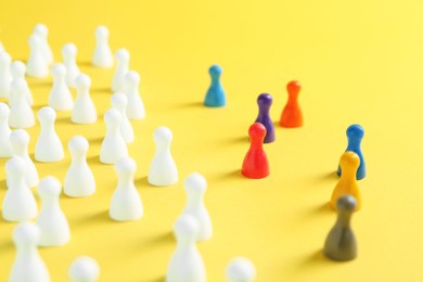 Photo of Colorful pawns on yellow background, closeup. Social inclusion concept