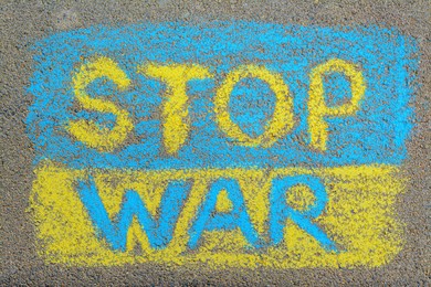 Ukrainian flag with words Stop War drawn with colorful chalks on asphalt outdoors, top view