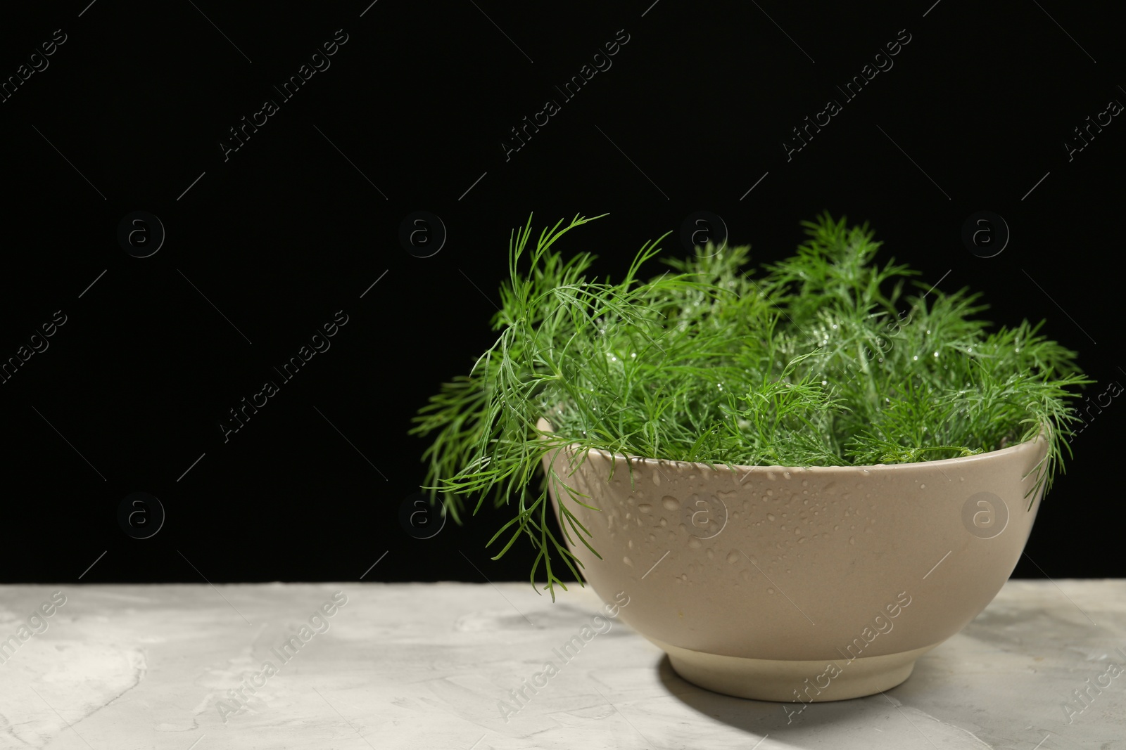 Photo of Bowl of fresh green dill with water drops on light grey table. Space for text