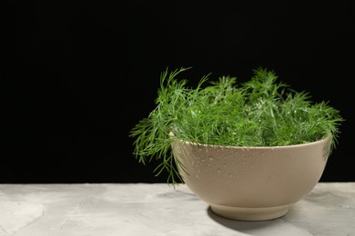 Bowl of fresh green dill with water drops on light grey table. Space for text