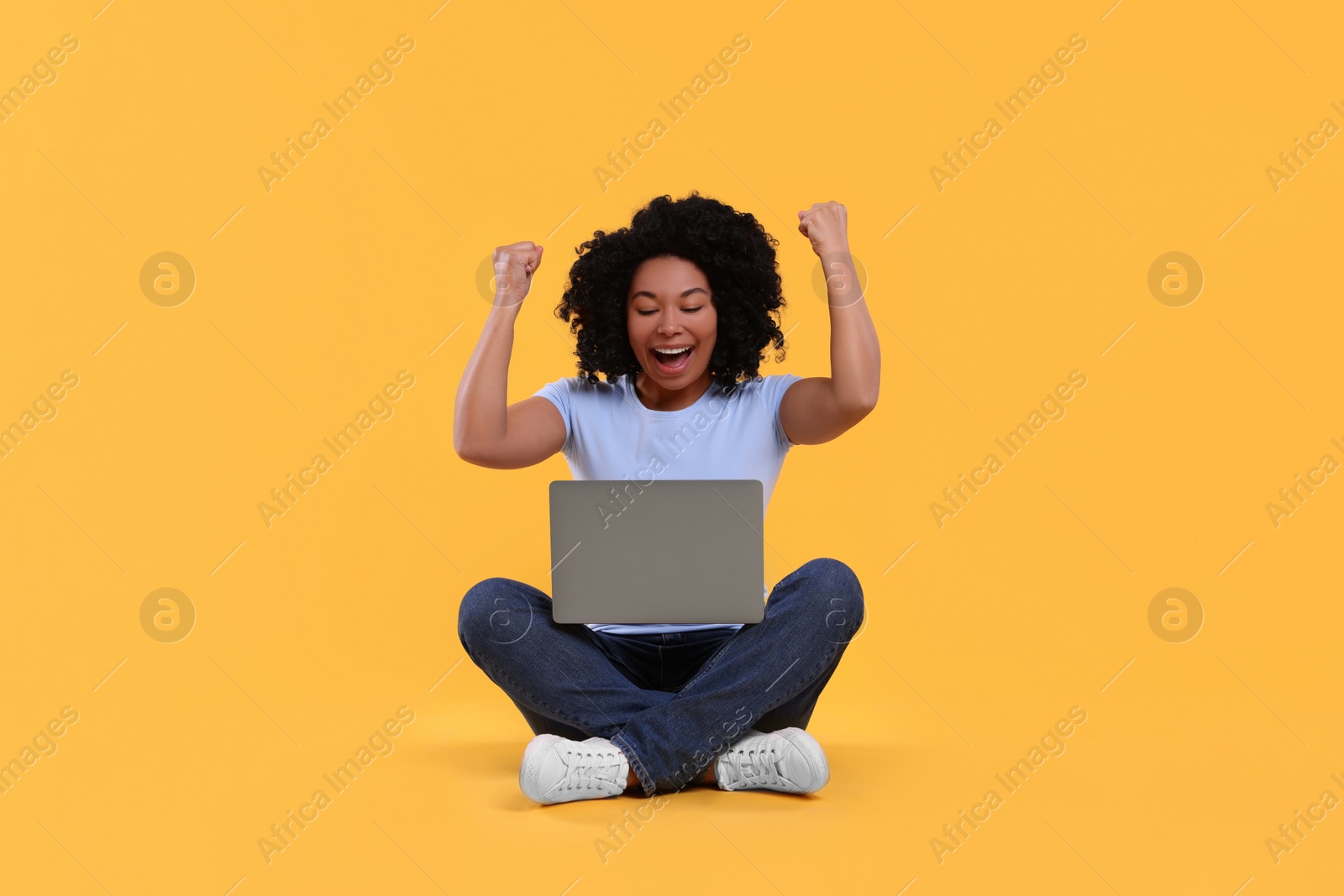 Photo of Emotional young woman with laptop on yellow background