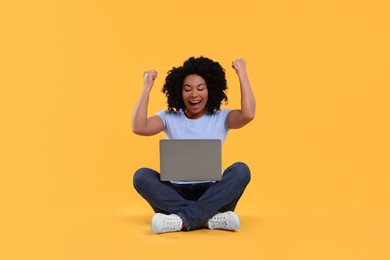 Emotional young woman with laptop on yellow background