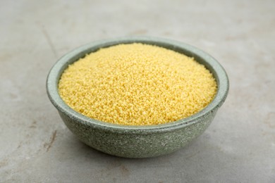 Bowl of raw couscous on light table, closeup