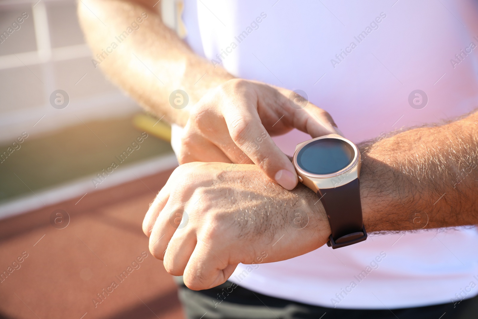 Photo of Man checking fitness tracker after training at stadium, closeup