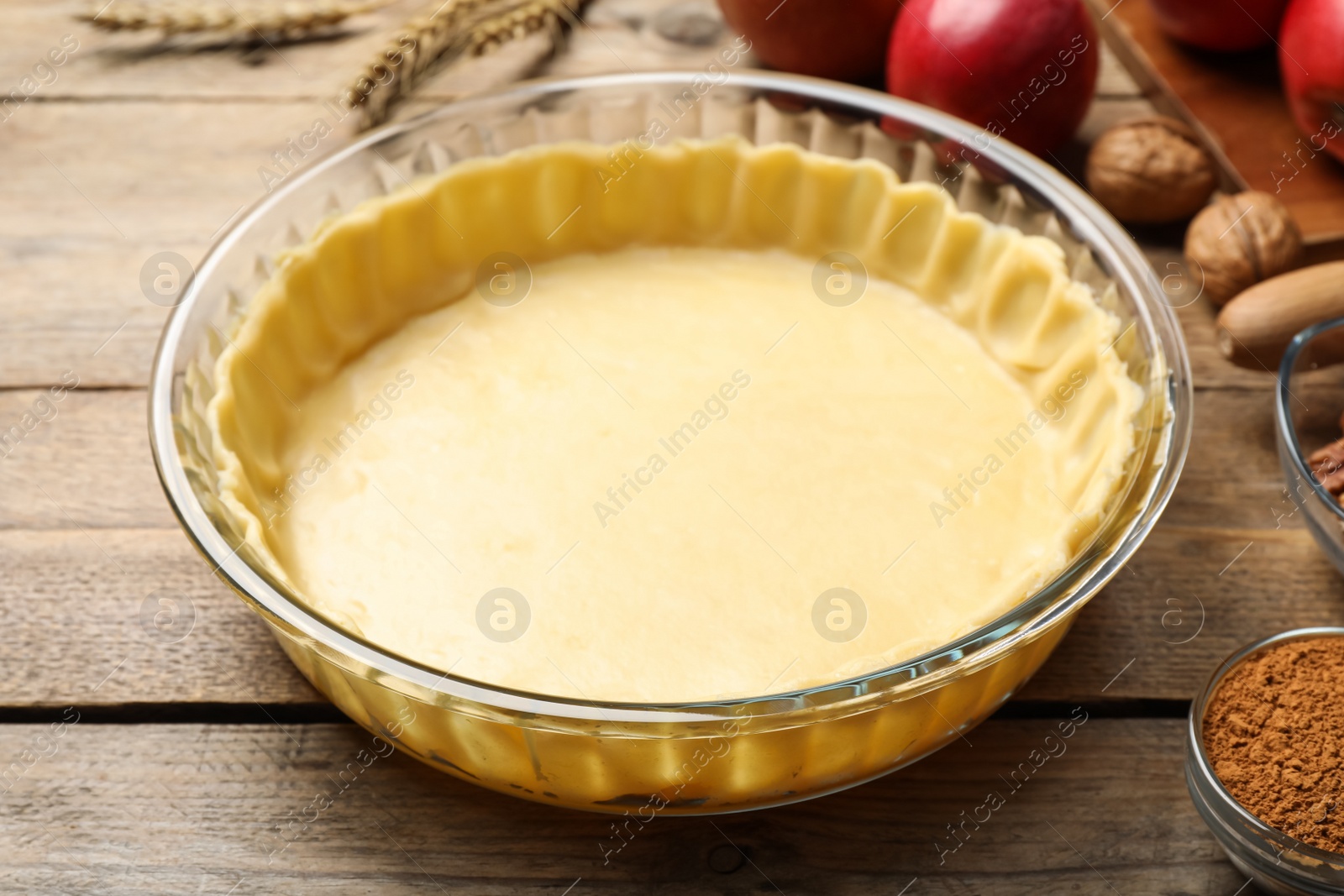 Photo of Raw dough and ingredients for apple pie on wooden table