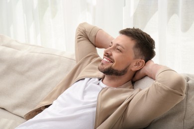 Photo of Handsome man relaxing on comfortable sofa indoors