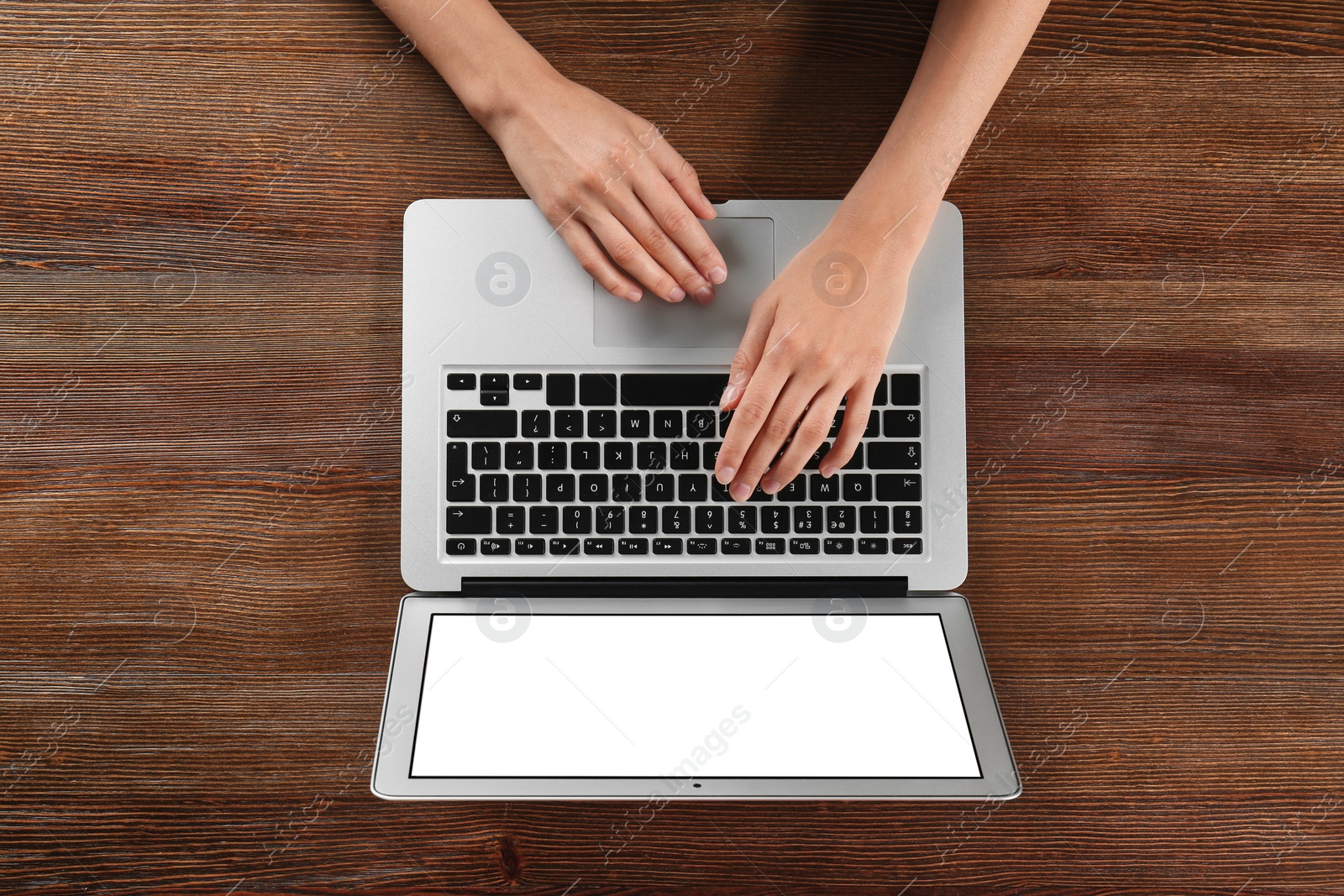 Photo of Young woman using laptop at wooden table, top view