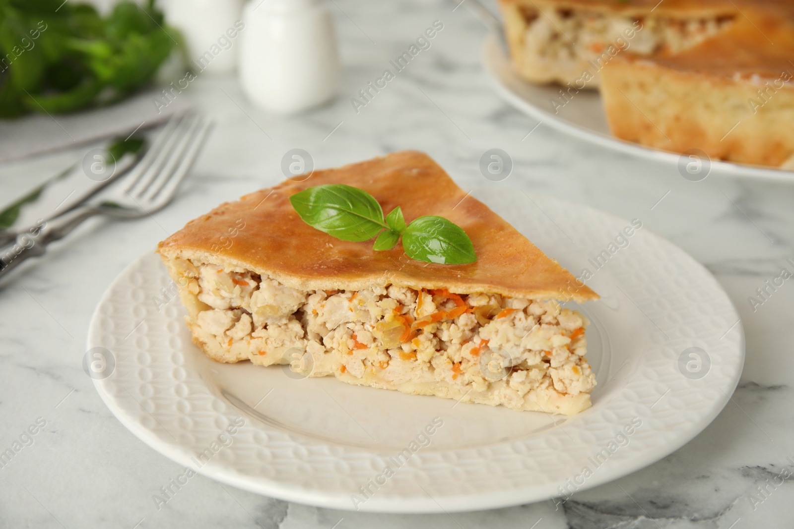 Photo of Piece of delicious pie with meat and basil on white marble table