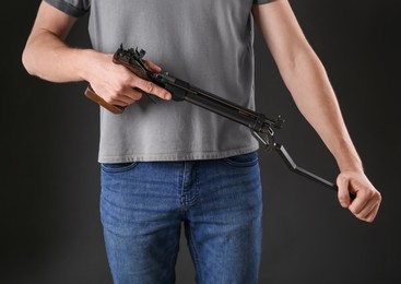 Photo of Gun shooting sport. Man holding standard pistol on dark background, closeup
