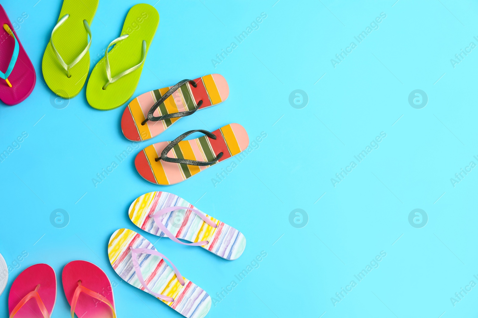 Photo of Flat lay composition with different flip flops on blue background, space for text. Summer beach accessories