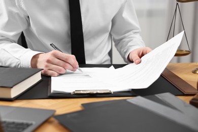 Photo of Lawyer working with documents at wooden table indoors, closeup