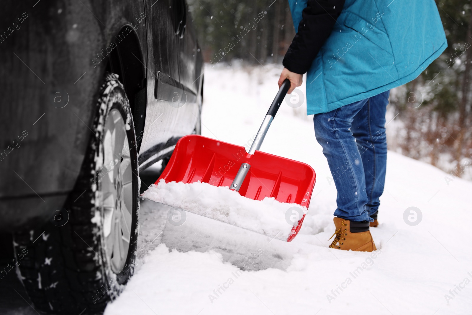 Photo of Man cleaning snow with shovel near stuck car outdoors