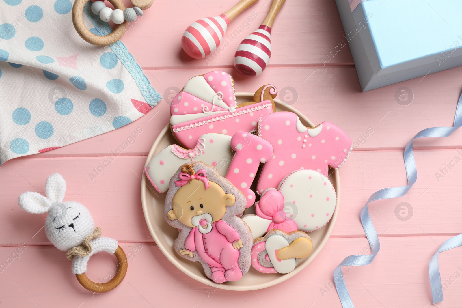 Photo of Tasty cookies of different shapes and toys on pink wooden table, flat lay. Baby shower party
