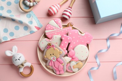 Photo of Tasty cookies of different shapes and toys on pink wooden table, flat lay. Baby shower party