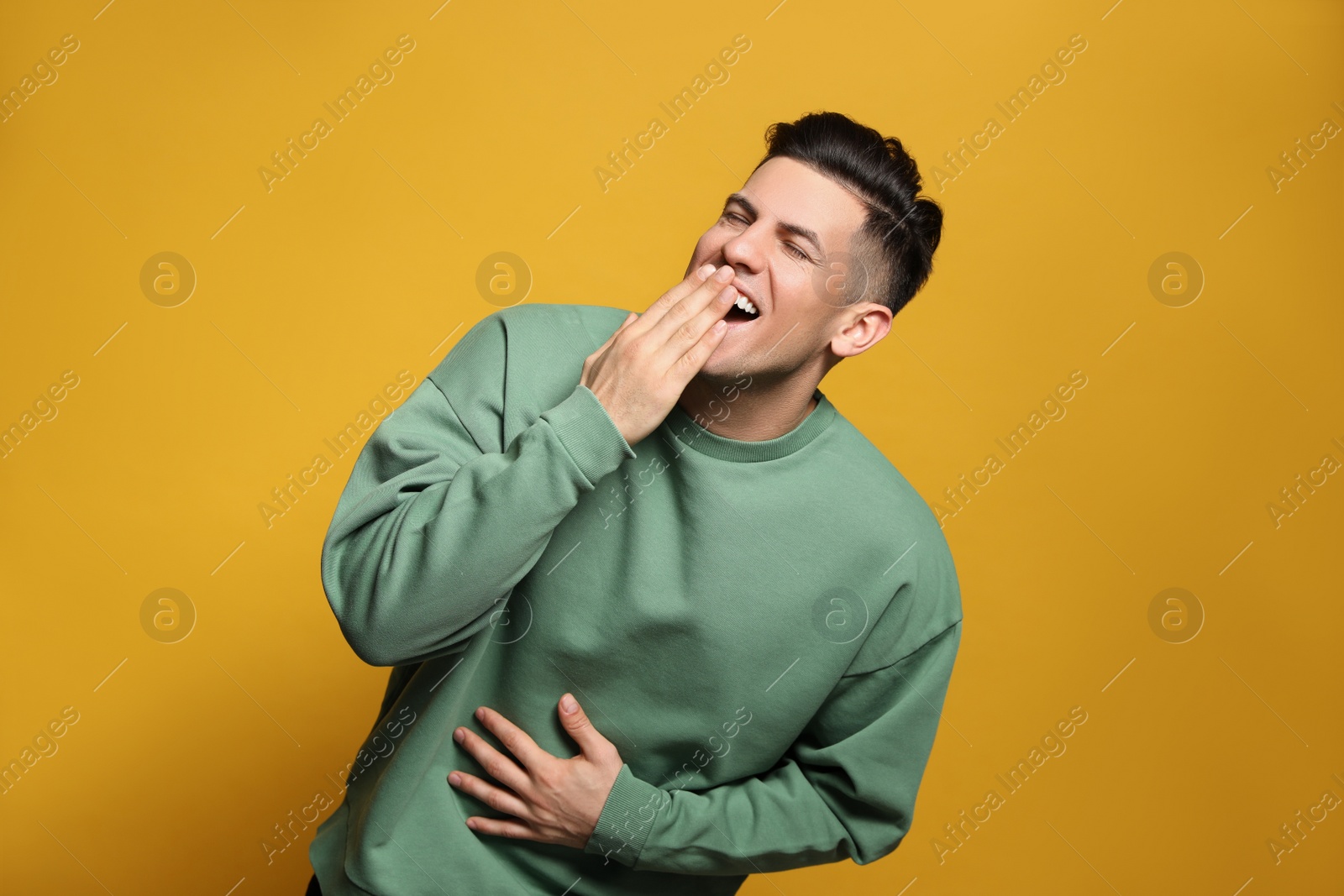 Photo of Handsome man laughing on yellow background. Funny joke