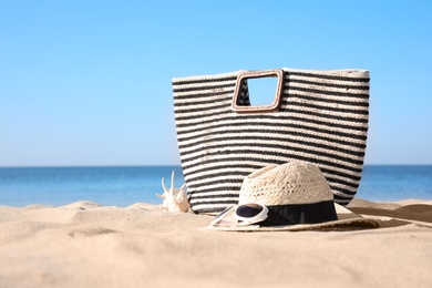 Stylish beach accessories on sand near sea